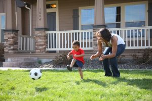kid playing soccer with his mom